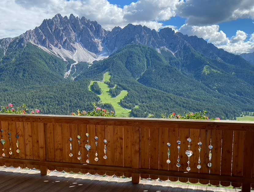familienurlaub_pustertal Familie sitzt auf einer Wiese und sieht ins Tal